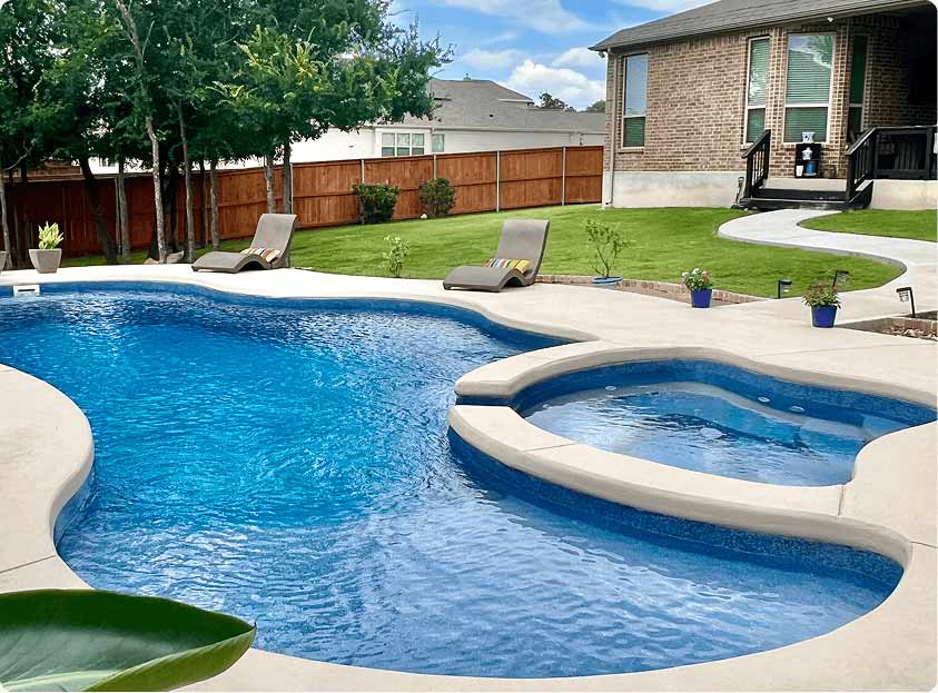 inground swimming pool with spa and light concrete decking