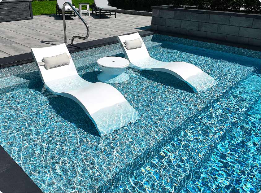 Large tanning ledge with lounge chairs in shallow end of pool