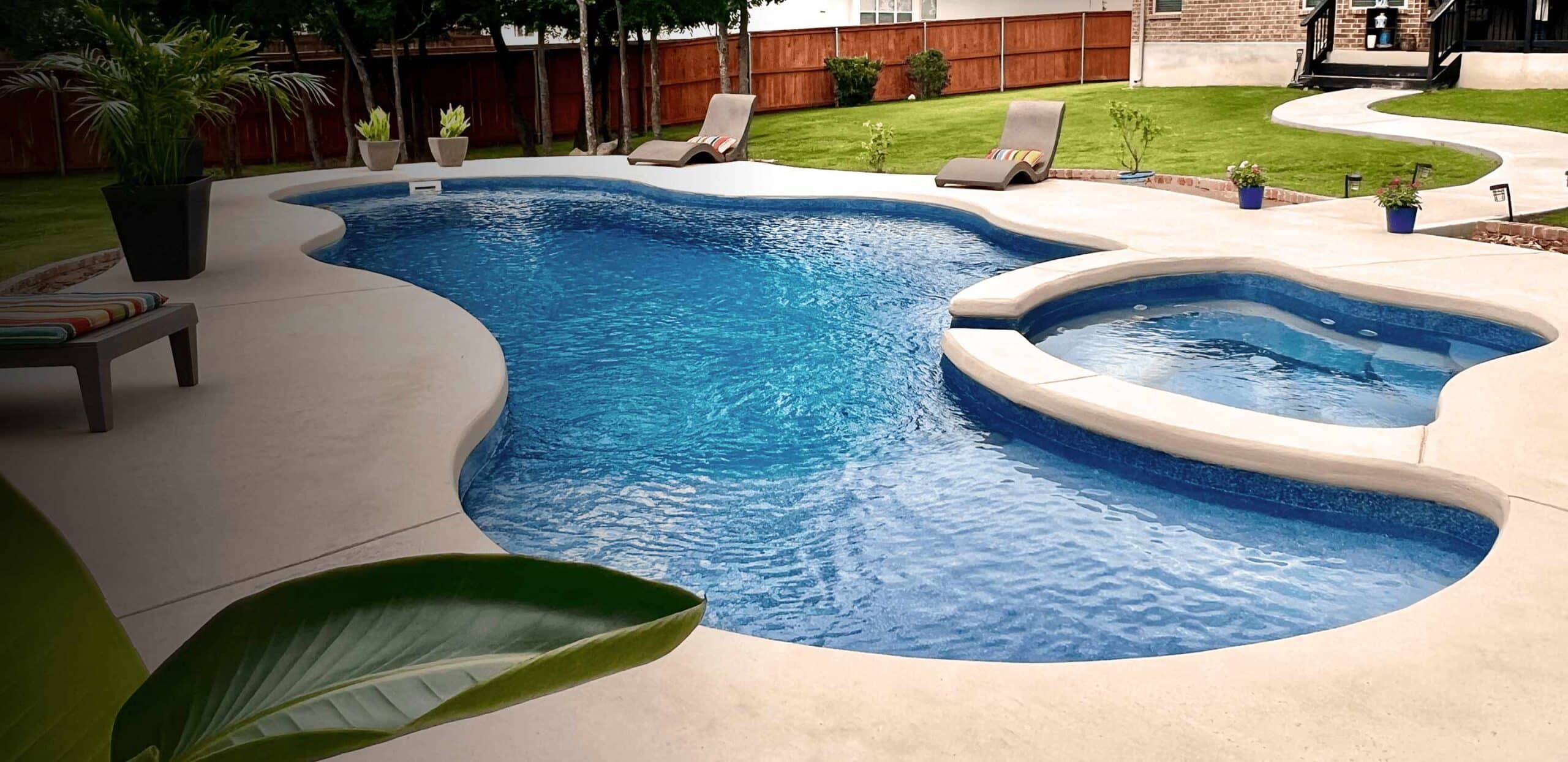 inground swimming pool with spa and light concrete decking